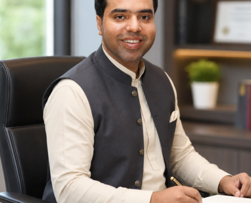Syed Raheel Shahzad — Executive Table Portrait Syed Raheel Shahzad (سيد راحيل شهزاد) seated at an executive table, professional portrait